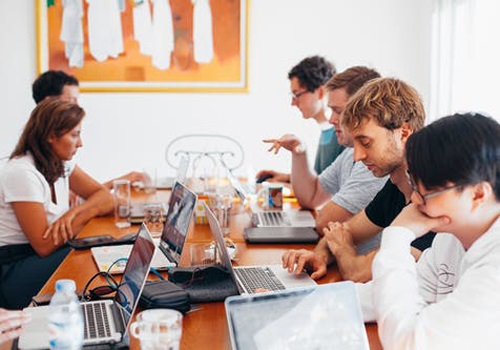 people sitting on chairs with their laptops on tables